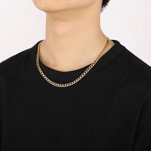Close-up of a gold-plated Cuban link necklace with polished finish worn by a model