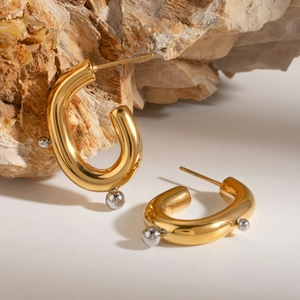 Detail of U-shaped gold earrings with silver beaded edges on natural stone display