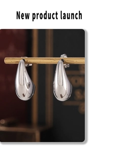 Detailed view of silver water drop earrings hanging on a metallic display stand