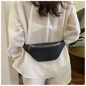 Detail of dark gray denim fanny pack with metal zipper worn by a model in nature setting