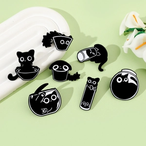 Detail view showing seven cute black cat alloy pins in funny poses on light green background