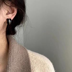 Minimalist black and gold vintage clip earrings on model wearing beige knit sweater