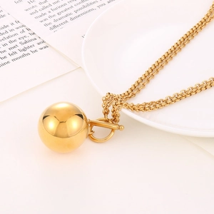 Detailaufnahme einer goldenen Hohlkugel-Halskette mit OT-Verschluss auf einem Keramikteller