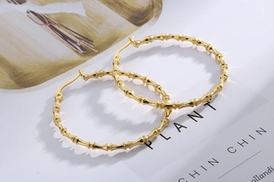 Detailed view of large golden bamboo-joint hoop earrings with polished metallic finish