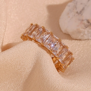 Detail of 18K gold plated ring featuring square-cut zircons on beige silk fabric