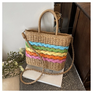 Detail of handmade straw bag with vibrant rainbow stripes and dual carrying handles