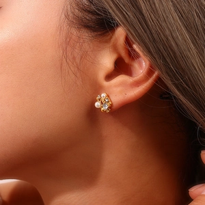 Close-up of gold flower earrings with pearls and rhinestones on a female model