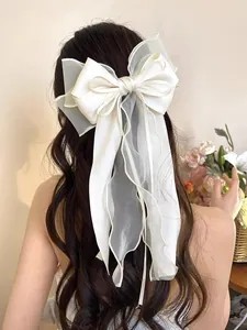 Detail of elegant white layered bow hair clip with long ribbons on wavy long hair