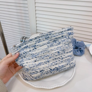 Detailed close-up of blue and white tweed fabric texture on a compact cosmetic bag