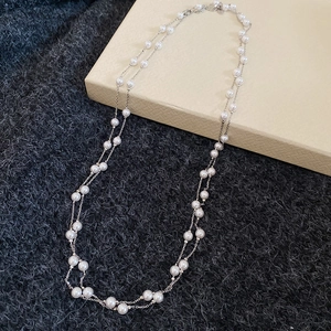 Détail d'un collier de perles argenté à double épaisseur sur fond en laine gris foncé