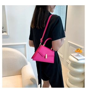 Detail of bright pink leather handbag with gold metal clasp and detachable shoulder strap