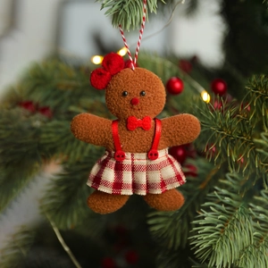 Detailed close-up of a gingerbread man plush ornament hanging on a festive Christmas tree branch