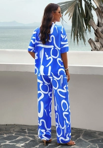 Rear view of woman in blue resort wear with white floral prints on a seaside terrace