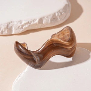 Detail showing wavy acrylic bangle in amber brown with translucent marble texture