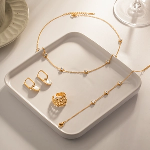 Detail of gold jewelry set with zircon necklace, bracelet and seashell inlay earrings