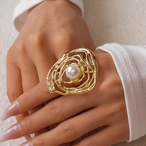Macro detail of gold irregular hollow ring with a single white pearl on hand