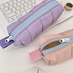 Quilted soft pencil case in lavender and coral with light blue zippers on a desk