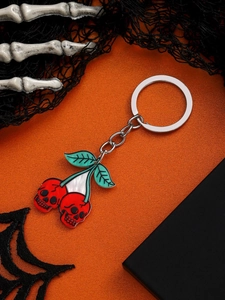Detail of red skull cherry keychain with green leaves on orange festive background