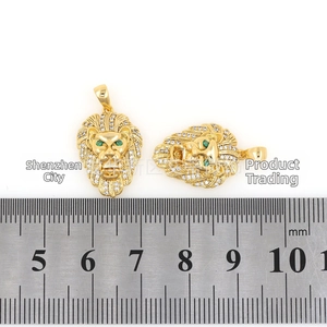 Macro view of gold lion head pendant with micro-pave cubic zirconia and green gem eyes