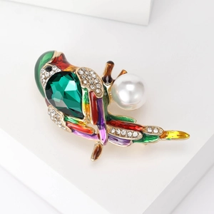 Close-up of bird brooch with colorful enamel, sparkling crystals and white pearl accent