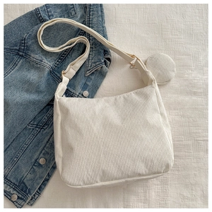 Detailed texture of white corduroy tote bag with round coin purse on denim jacket