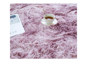 Close-up of soft plush gradient pink purple round rug with a cup and magazine