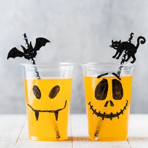 Halloween party cups with spooky face prints and decorative bat and cat straw toppers