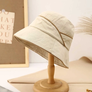 Detail of beige cotton linen bucket hat with brown piping on a wooden display stand