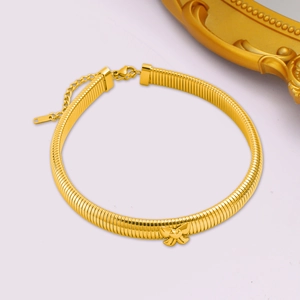 Détail d'un collier ras du cou doré avec nœud papillon, chaîne serpent et fermoir mousqueton