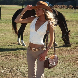Dettaglio del crop top bianco con scollo a V profondo, arricciature e lacci in stile western