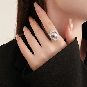 Close-up of a silver ring featuring a large grey pearl surrounded by sparkling zircons