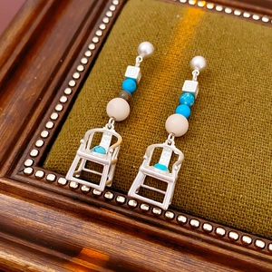 Detail of vintage chair earrings with turquoise accents and pearls on velvet