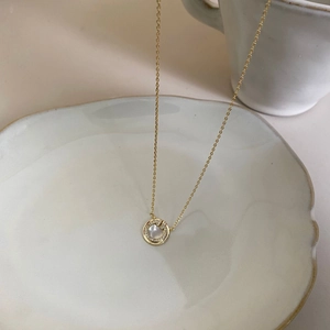 Close-up of golden necklace with a white mother-of-pearl pendant and diamond accent