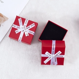 Three red jewelry gift boxes with white Crystal Jewelry ribbons on white faux fur background