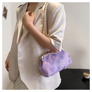 Detail of purple sequin floral evening bag with gold chain strap on model's shoulder