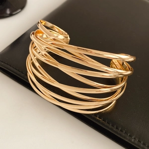 Detail view of multi-layer crisscross gold open cuff bracelet on leather background