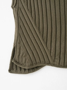 Macro detail of olive green ribbed knit vest featuring a clean side slit hemline