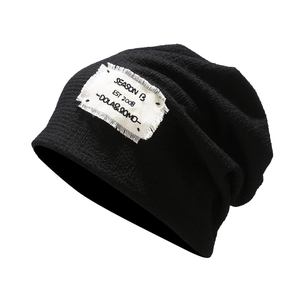 Minimalist black knit beanie featuring a white frayed patch and ribbed texture
