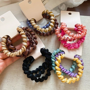 Vue détaillée d'élastiques à cheveux spirales multicolores sur tissu en dentelle