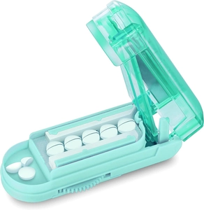 Detail view of mint green pill cutter with multi-slot tray and sharp metal blade
