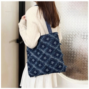 Detail of distressed denim tote bag with star pattern and quilted frayed edge finish