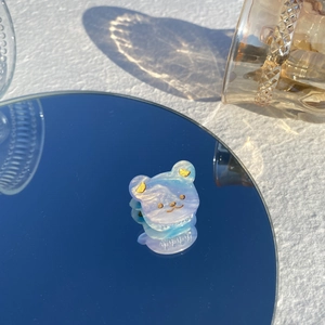 Détail d'une pince à cheveux ours en acétate dégradé bleu et violet sur miroir