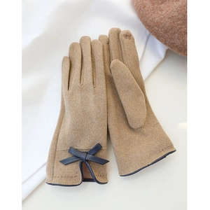 Detail of khaki suede gloves with dark blue bow accent on soft fabric background