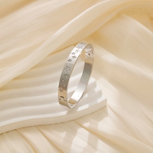 Macro shot of silver star-patterned bangle with cubic zirconia on silk fabric background