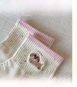 Close-up of cute puppy embroidery on beige socks with high-elastic pink ribbed cuffs