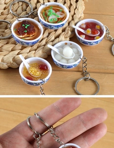 Macro detail of miniature Chinese food charms featuring porcelain bowls and metal keychains