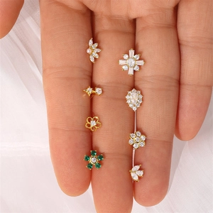 Detailed set of eight golden S925 sterling silver ear studs with zircon and pearls on palm