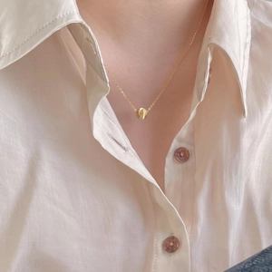 Detail of 925 sterling silver bead necklace worn by a model on a beige shirt background