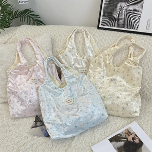 Close-up of four floral bear print velvet shoulder bags in pink, blue, and cream