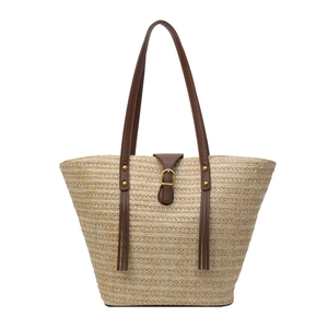 Large beige straw woven tote bag with brown leather straps and decorative tassels